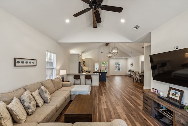 living room featuring dark hardwood / wood-style floors, beamed ceiling, high vaulted ceiling, and ceiling fan with notable chandelier