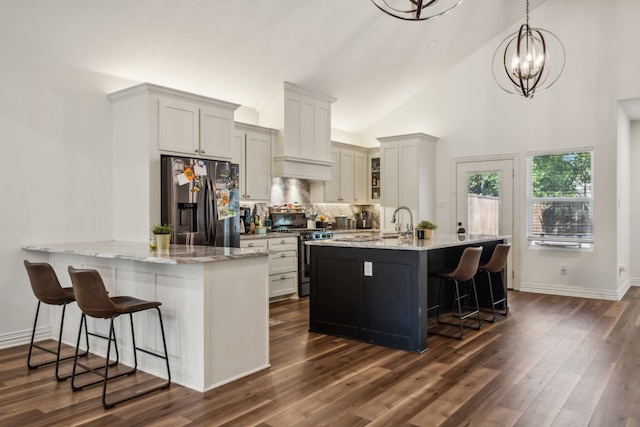 kitchen with kitchen peninsula, appliances with stainless steel finishes, a breakfast bar, dark hardwood / wood-style floors, and decorative light fixtures