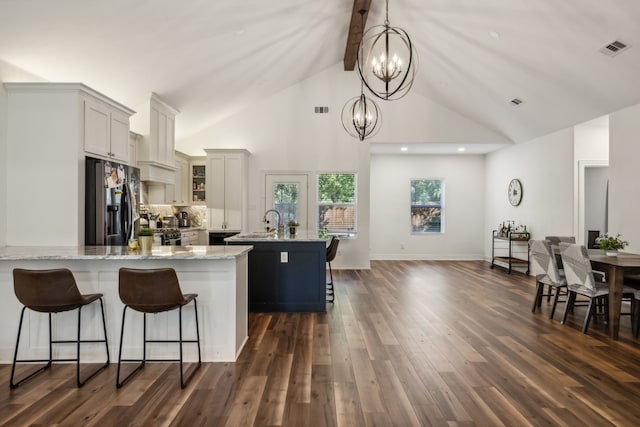 kitchen featuring hanging light fixtures, dark wood-type flooring, light stone counters, high vaulted ceiling, and stainless steel fridge with ice dispenser