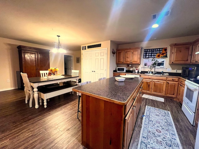 kitchen featuring a center island, sink, dark wood-type flooring, pendant lighting, and white appliances