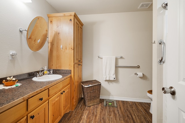 bathroom with wood-type flooring, vanity, and toilet