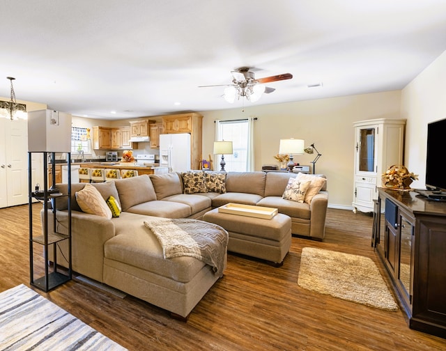 living room with dark hardwood / wood-style floors and ceiling fan with notable chandelier