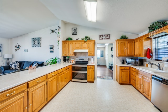 kitchen featuring lofted ceiling, stainless steel appliances, sink, light hardwood / wood-style floors, and tasteful backsplash