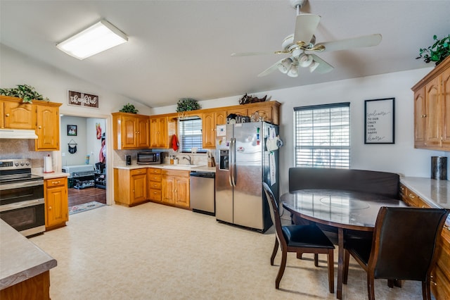 kitchen with lofted ceiling, sink, ceiling fan, appliances with stainless steel finishes, and tasteful backsplash