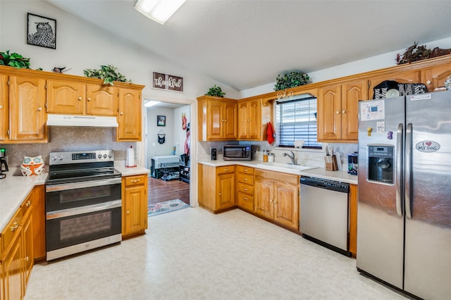 kitchen featuring sink, appliances with stainless steel finishes, lofted ceiling, and decorative backsplash