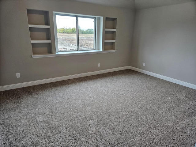 carpeted empty room featuring built in shelves