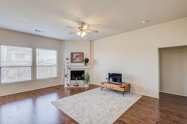 living room featuring dark wood-type flooring, ceiling fan, and a fireplace