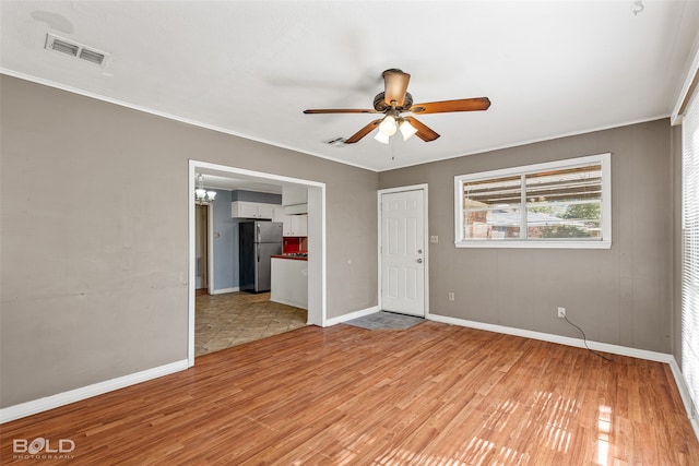 spare room with ceiling fan, ornamental molding, and light wood-type flooring