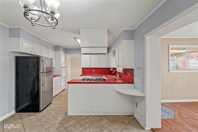 kitchen with white cabinets, sink, light wood-type flooring, ornamental molding, and appliances with stainless steel finishes