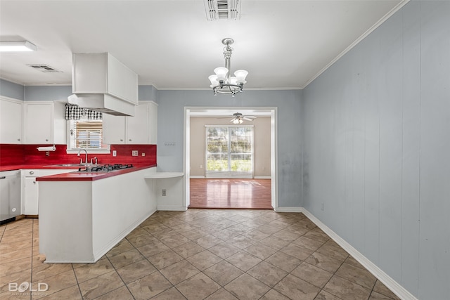 kitchen with tasteful backsplash, white cabinetry, ceiling fan with notable chandelier, and decorative light fixtures