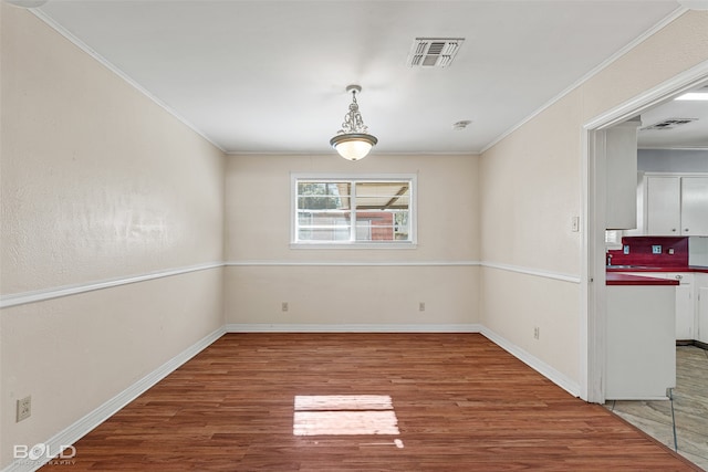 unfurnished dining area featuring hardwood / wood-style floors and ornamental molding