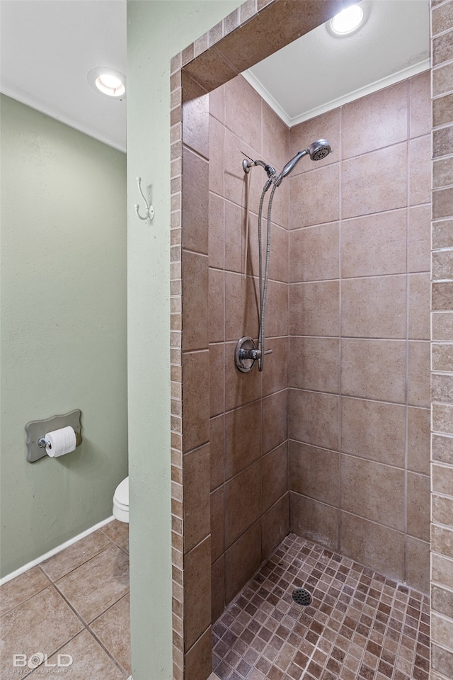 bathroom featuring tile patterned flooring, toilet, and a tile shower