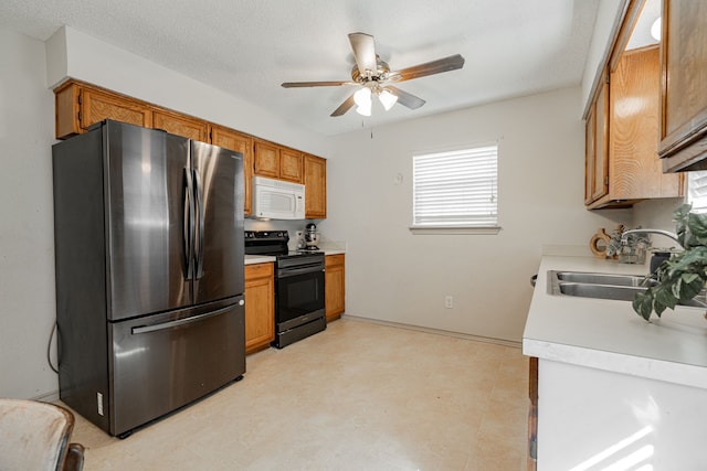 kitchen with stainless steel refrigerator, ceiling fan, sink, black electric range, and a textured ceiling