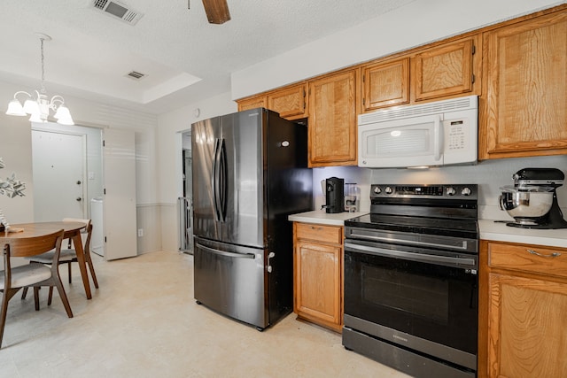 kitchen featuring pendant lighting, ceiling fan with notable chandelier, stainless steel appliances, and a textured ceiling