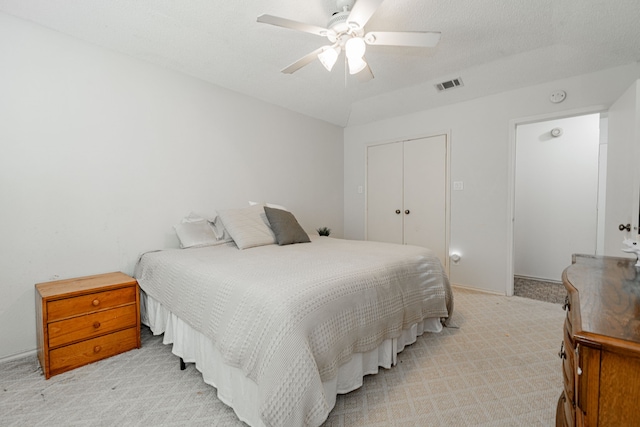 carpeted bedroom with a textured ceiling, a closet, and ceiling fan