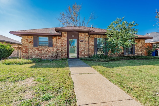 ranch-style home featuring a front lawn and brick siding