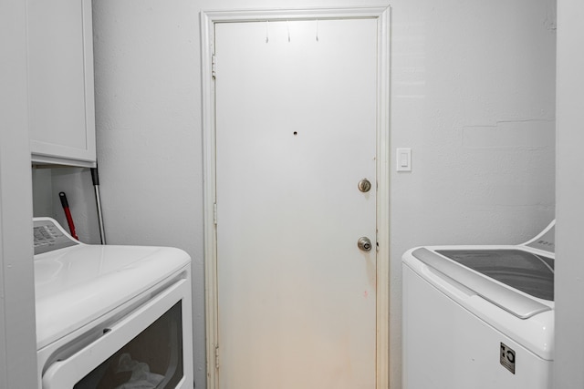 washroom with cabinets and washing machine and clothes dryer