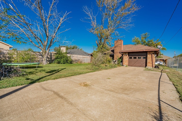 exterior space featuring a trampoline, a garage, and a lawn