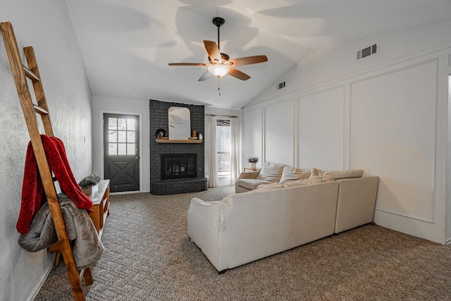 living room featuring ceiling fan, a fireplace, carpet, and vaulted ceiling