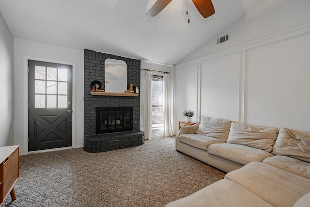 carpeted living room with visible vents, a ceiling fan, lofted ceiling, a brick fireplace, and a decorative wall