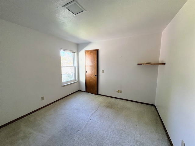 spare room featuring light colored carpet and a textured ceiling