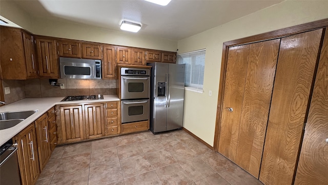 kitchen featuring backsplash, sink, stainless steel appliances, and light tile patterned flooring