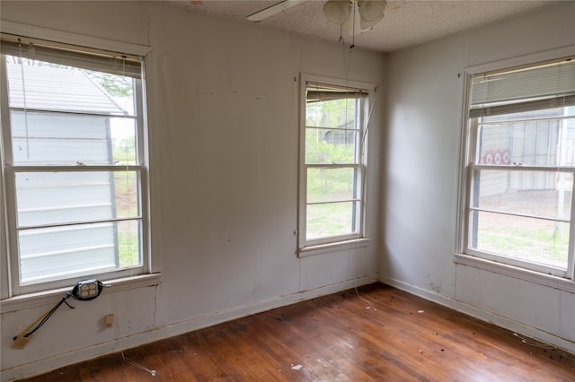 unfurnished room featuring dark hardwood / wood-style floors, a healthy amount of sunlight, a textured ceiling, and ceiling fan