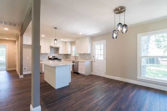 kitchen with appliances with stainless steel finishes, decorative light fixtures, dark hardwood / wood-style floors, and white cabinets