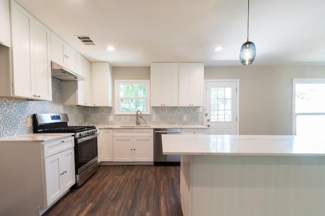 kitchen with sink, white cabinetry, stainless steel appliances, decorative light fixtures, and dark wood-type flooring