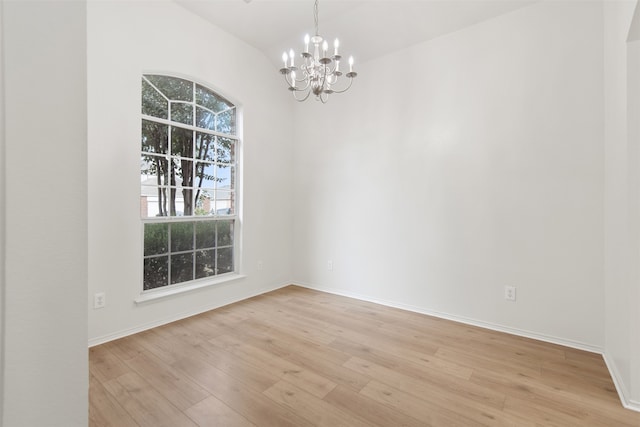 empty room with lofted ceiling, light hardwood / wood-style flooring, and a notable chandelier