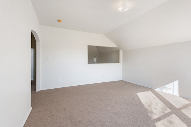 additional living space featuring light carpet and vaulted ceiling