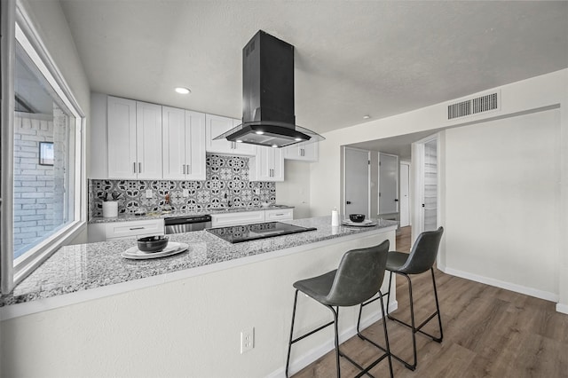 kitchen featuring island range hood, black electric stovetop, dishwasher, dark hardwood / wood-style floors, and white cabinetry