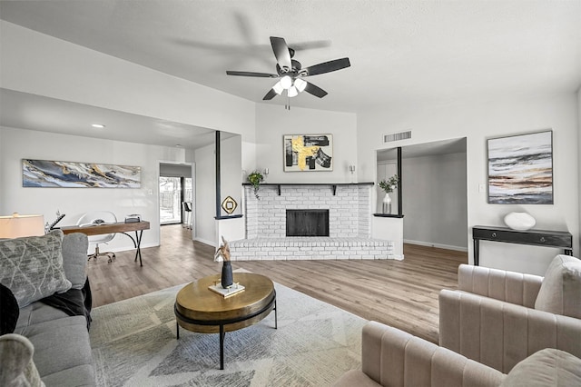 living room with light hardwood / wood-style floors, a fireplace, and ceiling fan