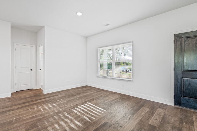 spare room featuring baseboards, wood finished floors, visible vents, and recessed lighting