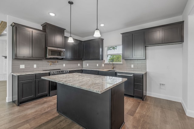 kitchen with stainless steel appliances, a sink, light stone countertops, baseboards, and dark wood-style flooring