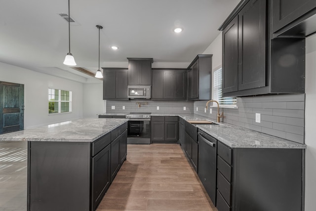 kitchen featuring a sink, visible vents, light stone counters, a kitchen island, and appliances with stainless steel finishes
