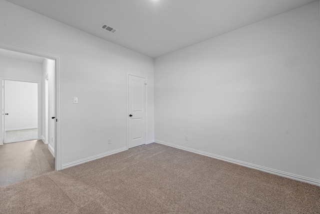 carpeted spare room with visible vents and baseboards
