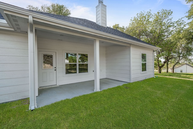 rear view of property featuring a patio area, a lawn, and a chimney