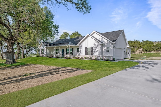 view of front facade with a front lawn, driveway, covered porch, a garage, and board and batten siding
