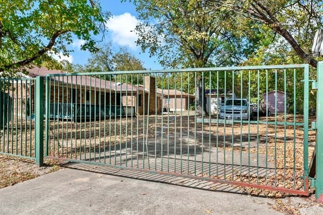 view of gate featuring a storage shed, fence, and an outdoor structure