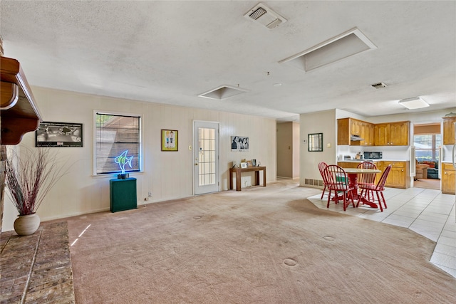 dining room featuring visible vents, attic access, a textured ceiling, and light colored carpet