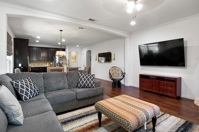 living room with dark hardwood / wood-style floors, ceiling fan, and ornamental molding