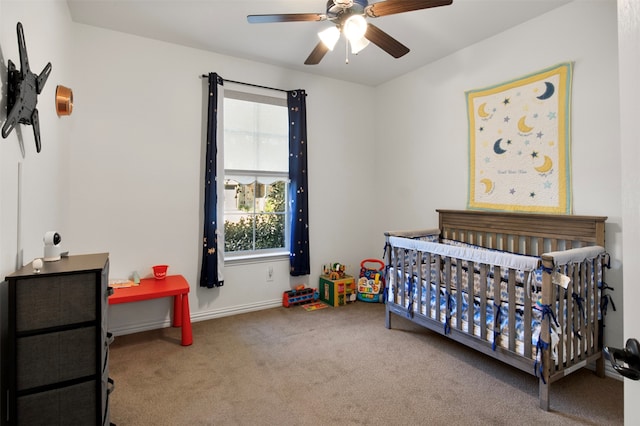 carpeted bedroom featuring a crib and ceiling fan