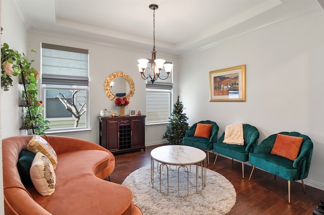 sitting room with an inviting chandelier, a raised ceiling, dark wood-type flooring, and crown molding