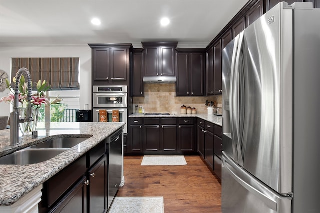 kitchen featuring light stone countertops, dark hardwood / wood-style flooring, backsplash, stainless steel appliances, and sink