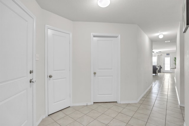 hallway featuring a textured ceiling and light tile patterned floors