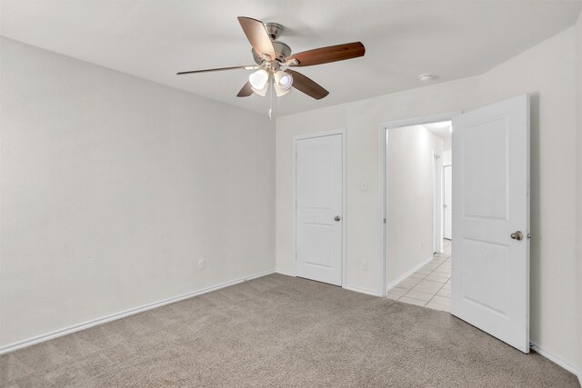 unfurnished bedroom featuring light carpet, a closet, and ceiling fan