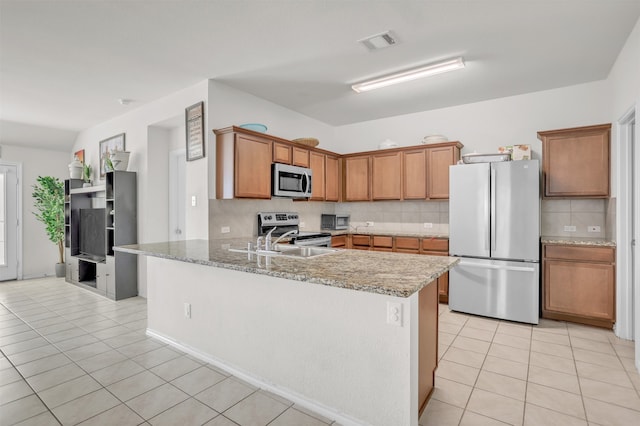 kitchen featuring tasteful backsplash, appliances with stainless steel finishes, sink, kitchen peninsula, and light stone counters