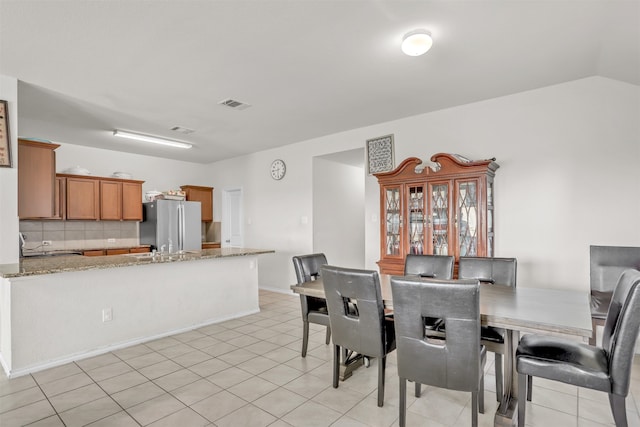 dining area with vaulted ceiling and light tile patterned floors