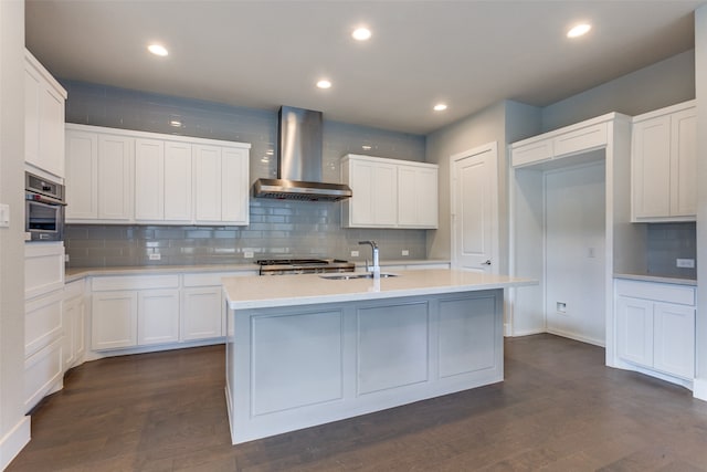 kitchen with sink, an island with sink, wall chimney range hood, and dark hardwood / wood-style floors